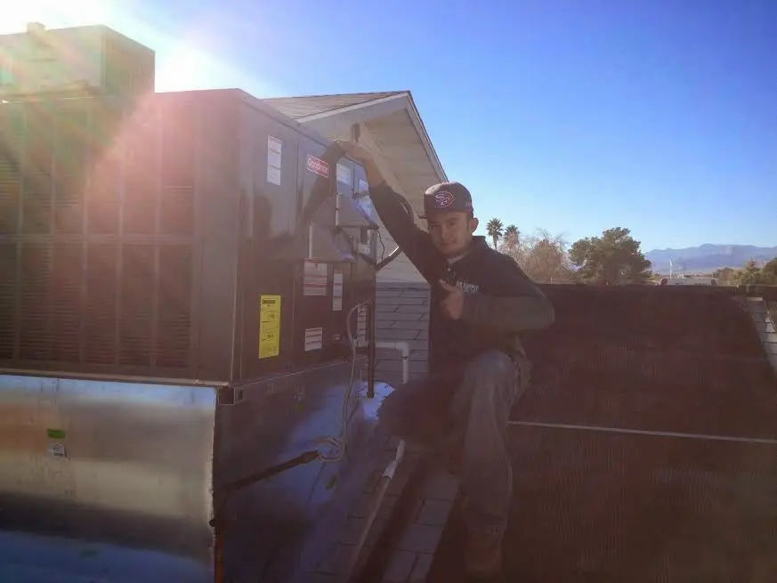 HVAC technician performing AC Tune-Up on a rooftop unit in Elsa